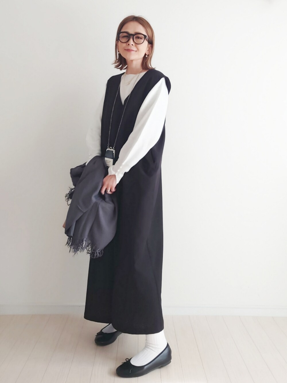 ブラック系のジャンパースカート、ホワイト系のニット/セーター、ブラック系のバレエシューズを着用したレディースの冬コーディネートの2枚目の写真