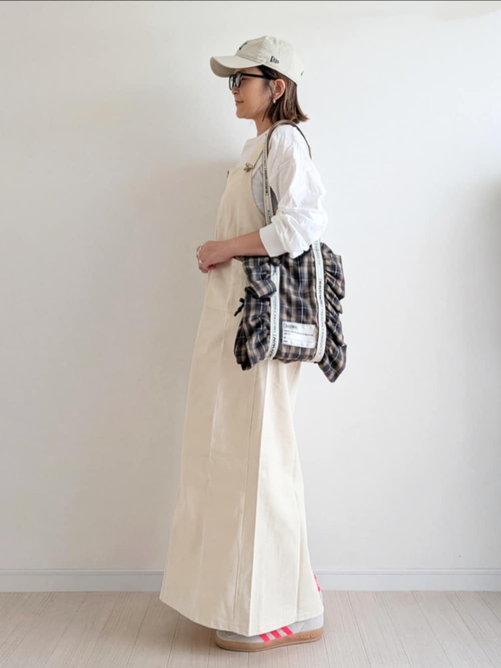 ホワイト系のジャンパースカート、ホワイト系のTシャツ/カットソー、ベージュ系のスニーカーを着用したレディースの秋コーディネートの2枚目の写真