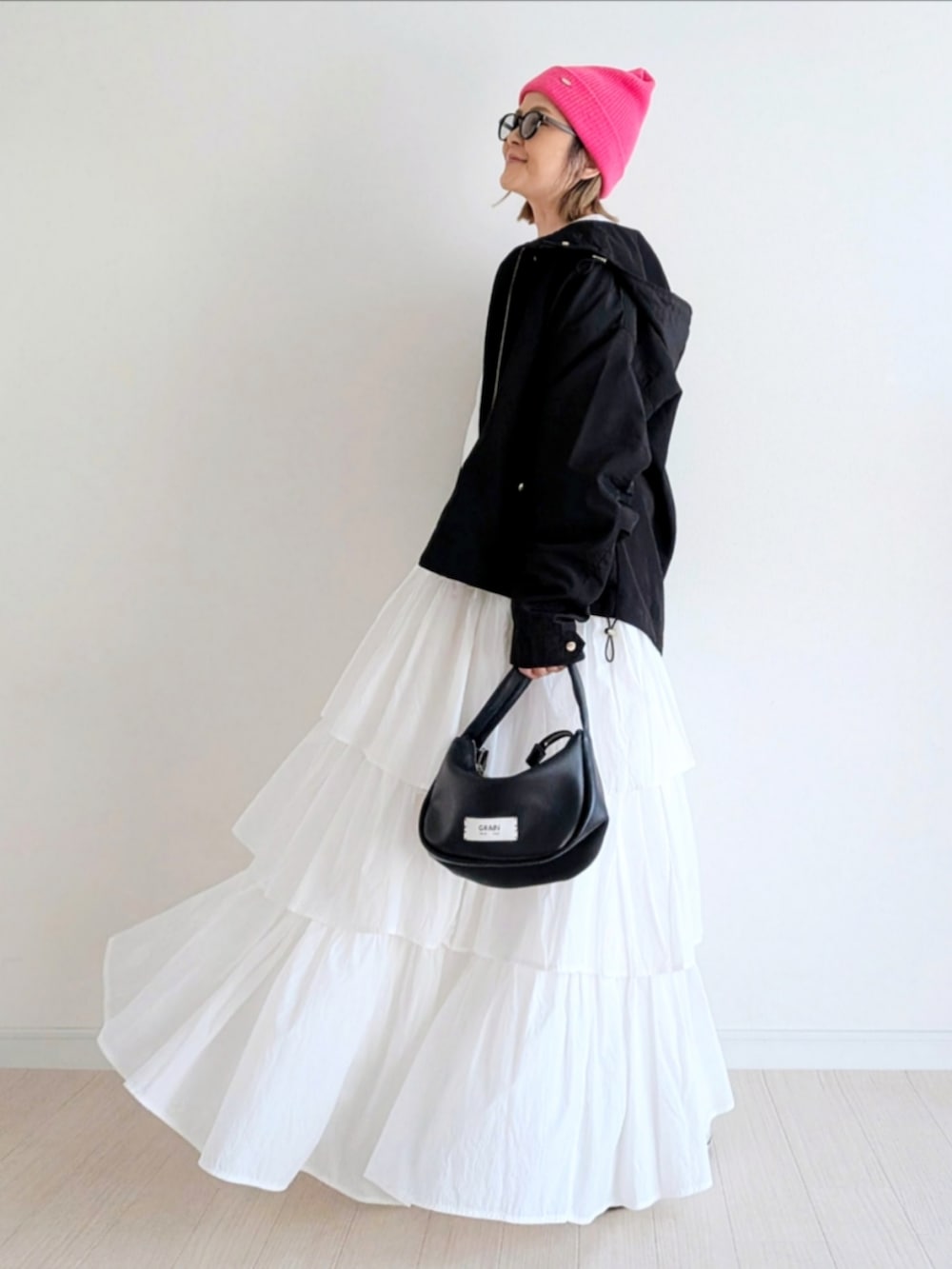 ホワイト系のスカート、ブラック系のハンドバッグ、ブラック系のマウンテンパーカーを着用したレディースの冬コーディネートの2枚目の写真