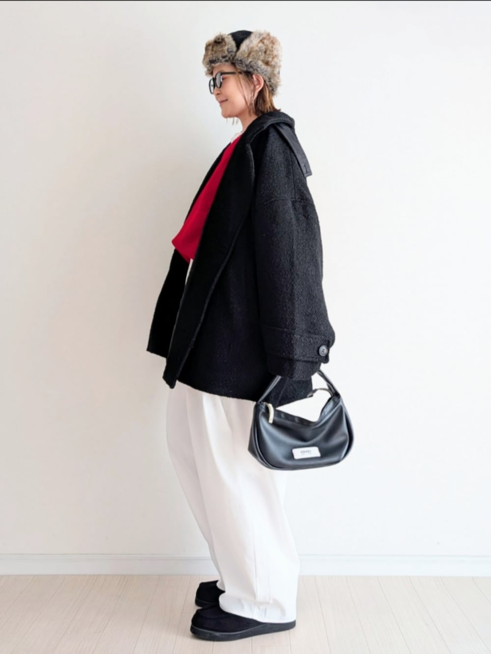 ブラック系のピーコート、レッド系のニット/セーターを着用したレディースの冬コーディネートの4枚目の写真