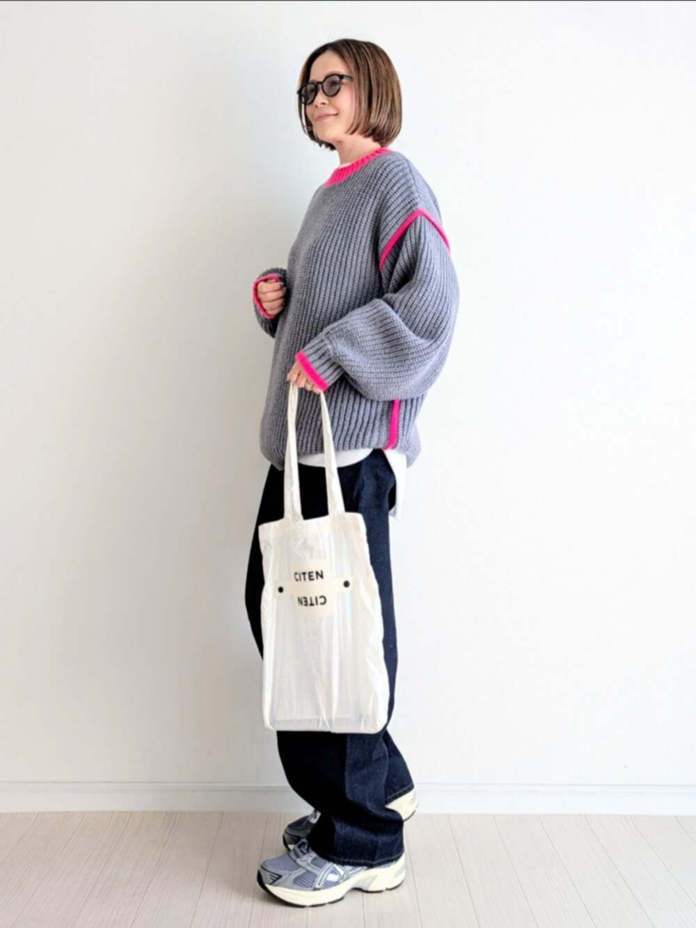 グレー系のニット/セーター、ホワイト系のトートバッグ、ブルー系のデニムパンツを着用したレディースの冬コーディネートの2枚目の写真