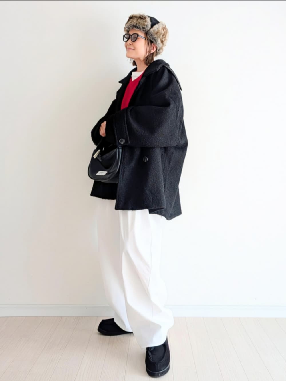 ブラック系のピーコート、レッド系のニット/セーターを着用したレディースの冬コーディネートの3枚目の写真