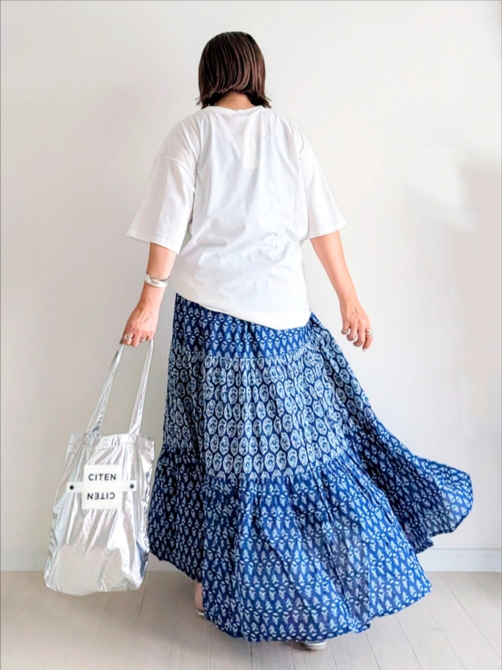 ブルー系のスカート、ホワイト系のTシャツ/カットソー、シルバー系のトートバッグを着用したレディースの夏コーディネートの4枚目の写真