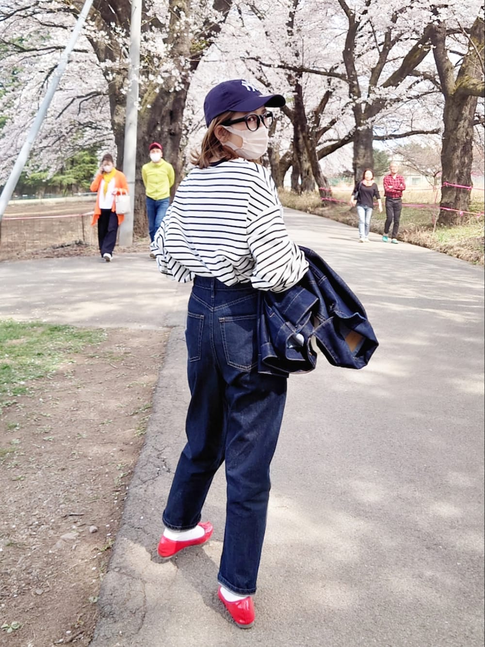 ブラック系のTシャツ/カットソー、ブルー系のデニムパンツ、ホワイト系のハンドバッグを着用したレディースの春コーディネートの3枚目の写真