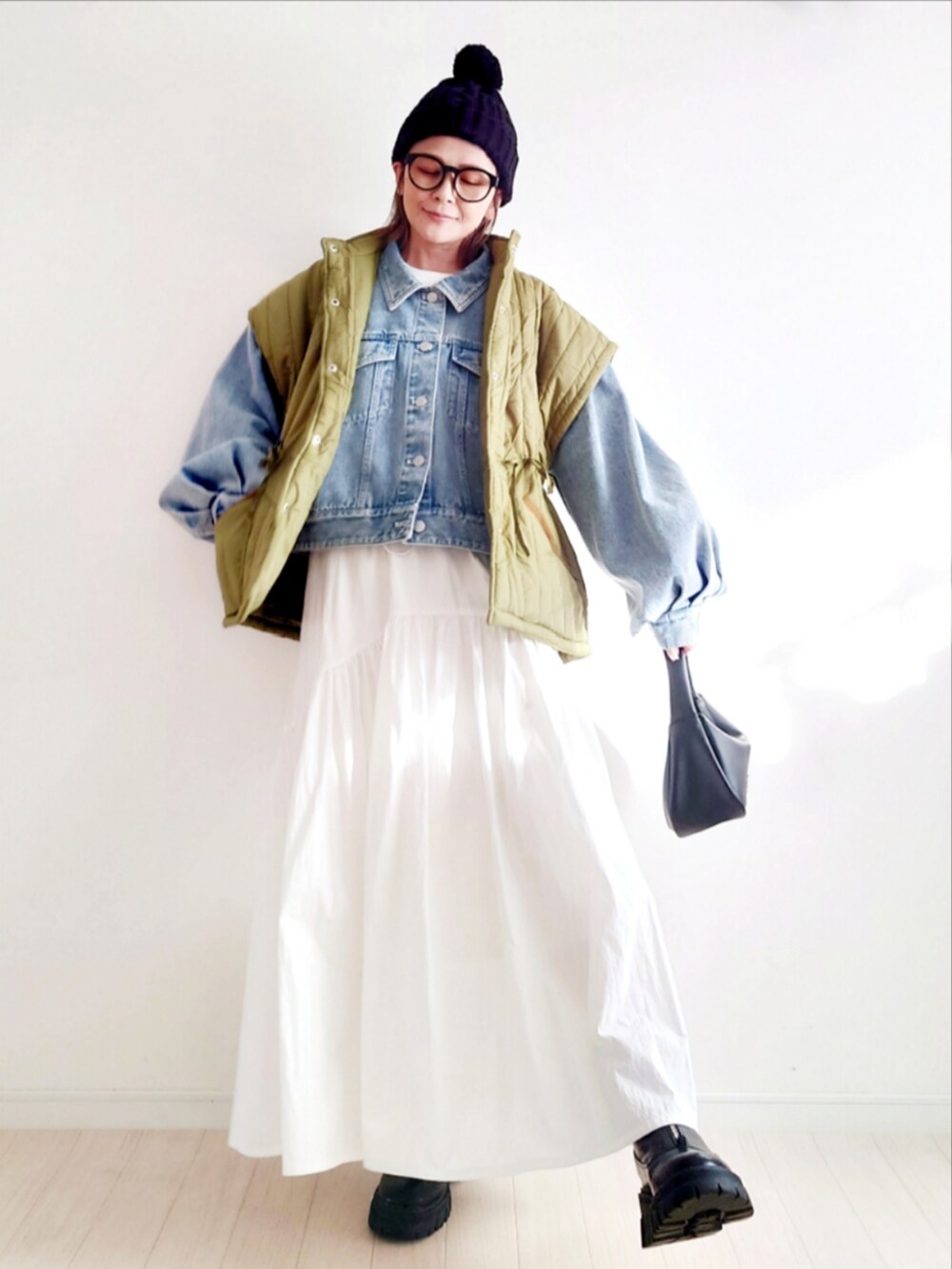 ブルー系のデニムジャケット、ホワイト系のスカート、ブラック系のブーツを着用したレディースの冬コーディネートの3枚目の写真