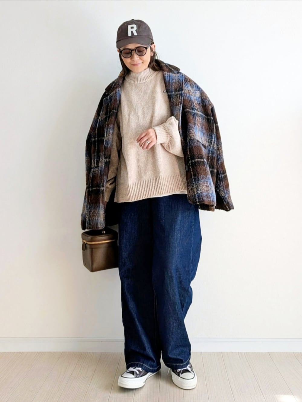ブラウン系のテーラードジャケット、ベージュ系のニット/セーター、ブルー系のデニムパンツを着用したレディースの秋コーディネートの4枚目の写真