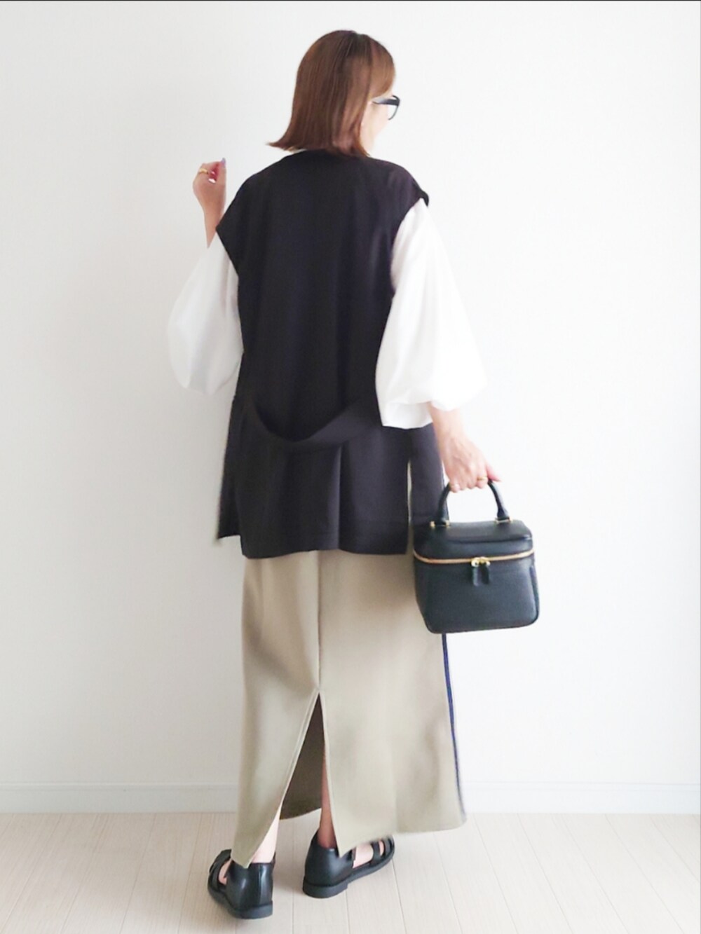 ブルー系のスカート、ホワイト系のシャツ/ブラウス、ブラック系のベストを着用したレディースの春コーディネートの5枚目の写真