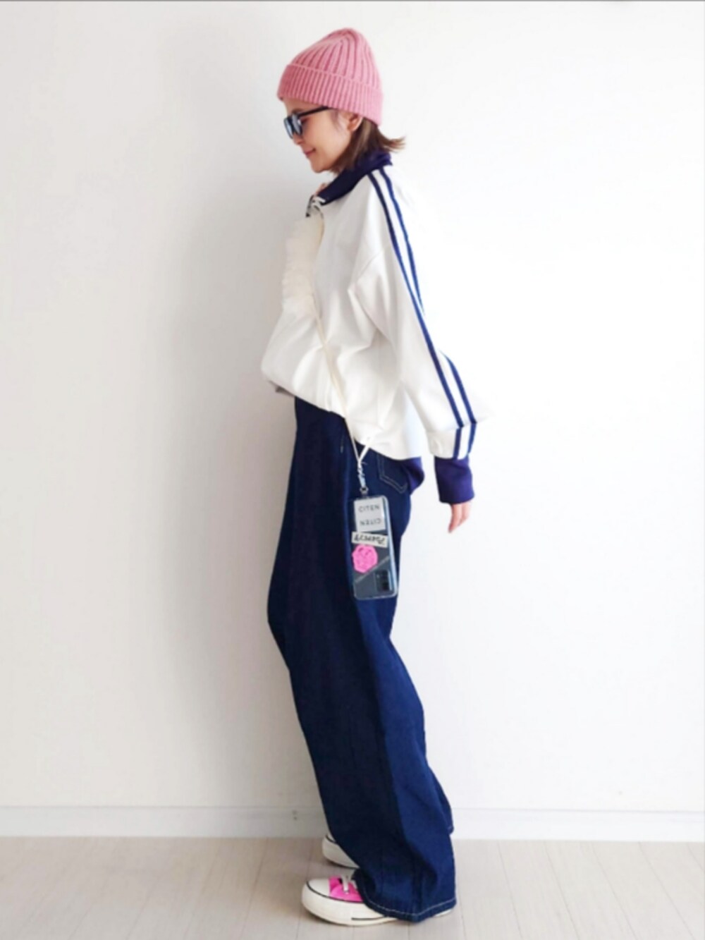 ホワイト系のジャージ、ブルー系のデニムパンツ、ピンク系のスニーカーを着用したレディースの冬コーディネートの4枚目の写真