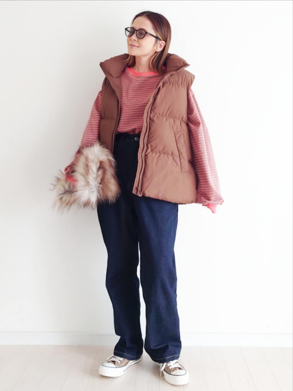 ブラウン系のTシャツ/カットソー、ブルー系のデニムパンツ、ブラウン系のダウンベストを着用したレディースの秋コーディネートの4枚目の写真