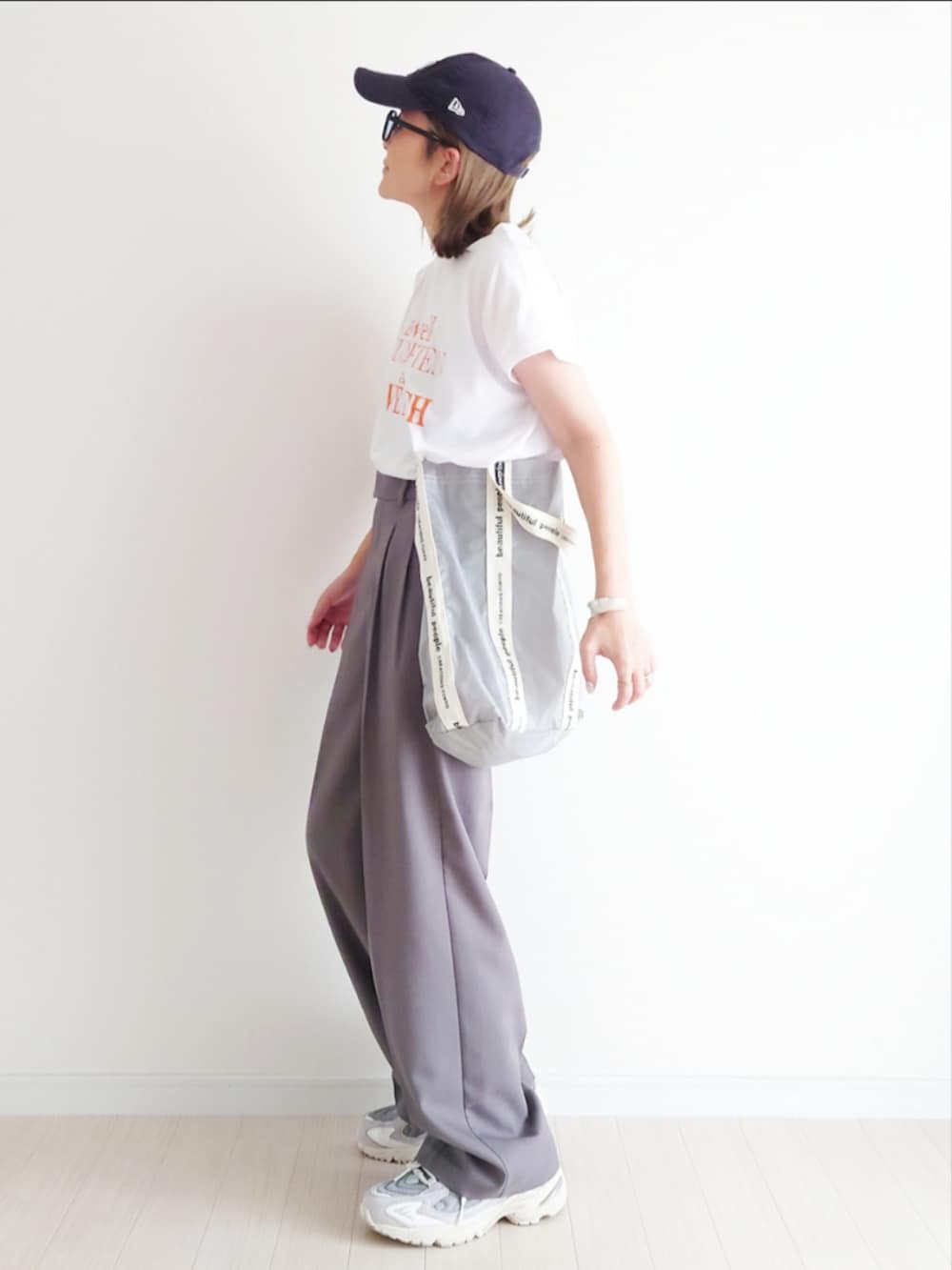 ホワイト系のTシャツ/カットソー、グレー系のスラックス、グレー系のスニーカーを着用したレディースの夏コーディネートの4枚目の写真