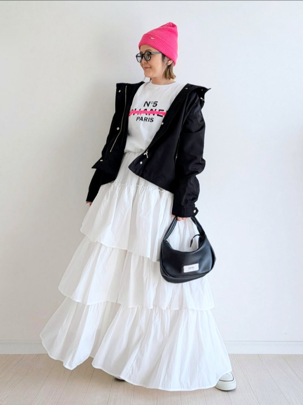 ホワイト系のスカート、ブラック系のハンドバッグ、ブラック系のマウンテンパーカーを着用したレディースの冬コーディネートの4枚目の写真