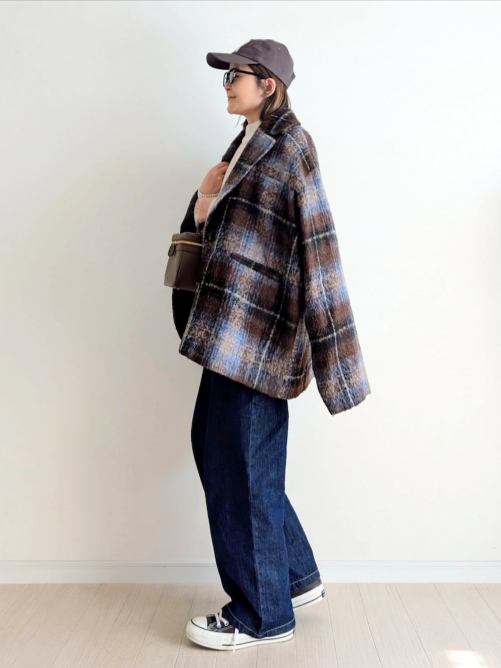 ブラウン系のテーラードジャケット、ベージュ系のニット/セーター、ブルー系のデニムパンツを着用したレディースの秋コーディネートの2枚目の写真