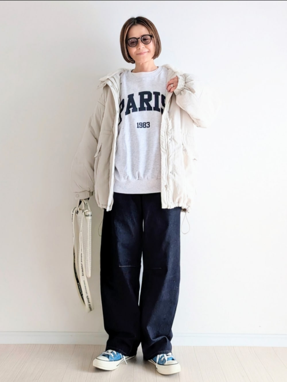 ホワイト系のブルゾン、ホワイト系のスウェット、ブルー系のデニムパンツを着用したレディースの冬コーディネートの2枚目の写真