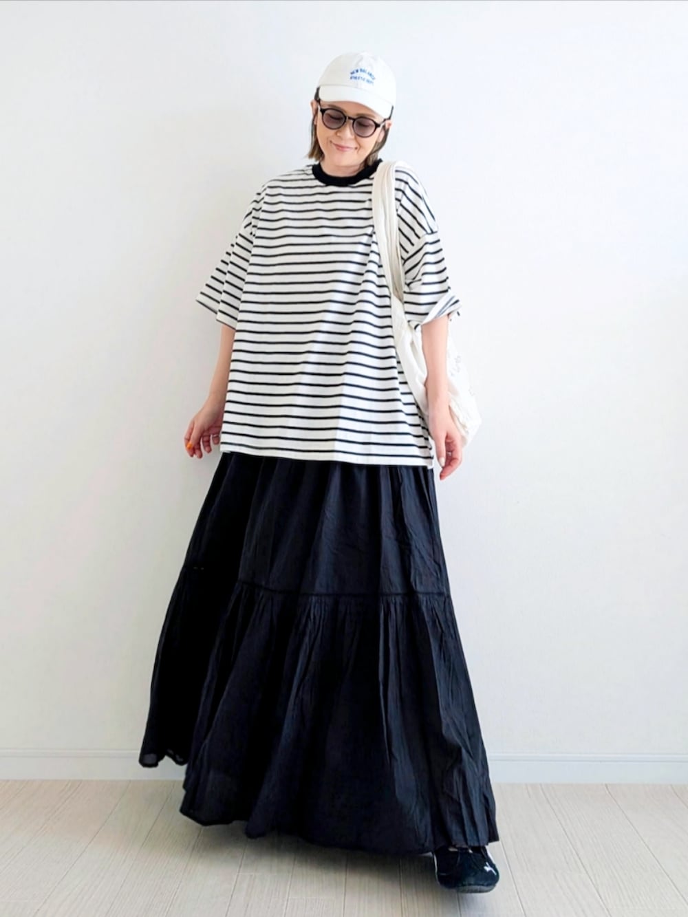 ブラック系のTシャツ/カットソー、ブラック系のスカート、ブラック系のスニーカーを着用したレディースの春コーディネートの2枚目の写真