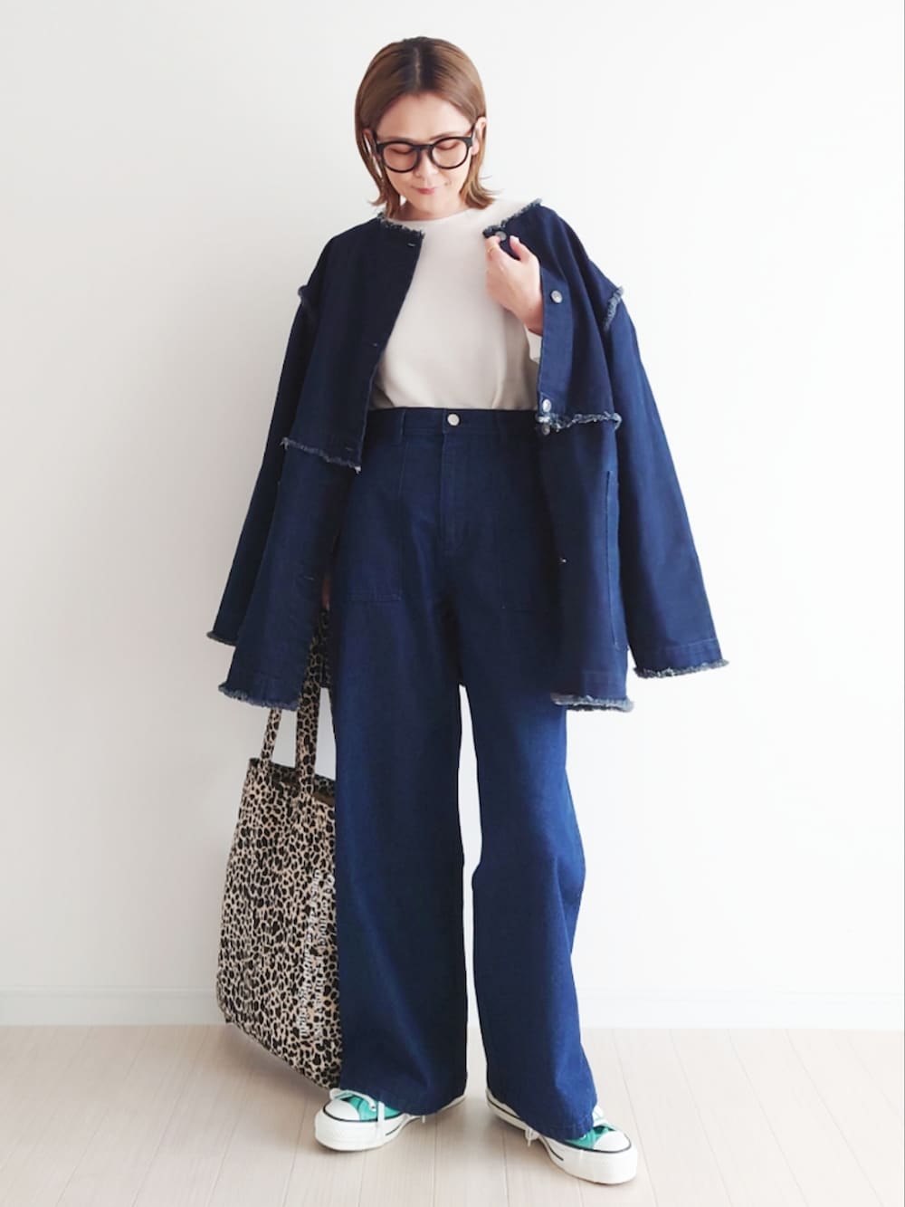 ブルー系のデニムジャケット、ホワイト系のニット/セーター、グリーン系のスニーカーを着用したレディースの春コーディネートの2枚目の写真