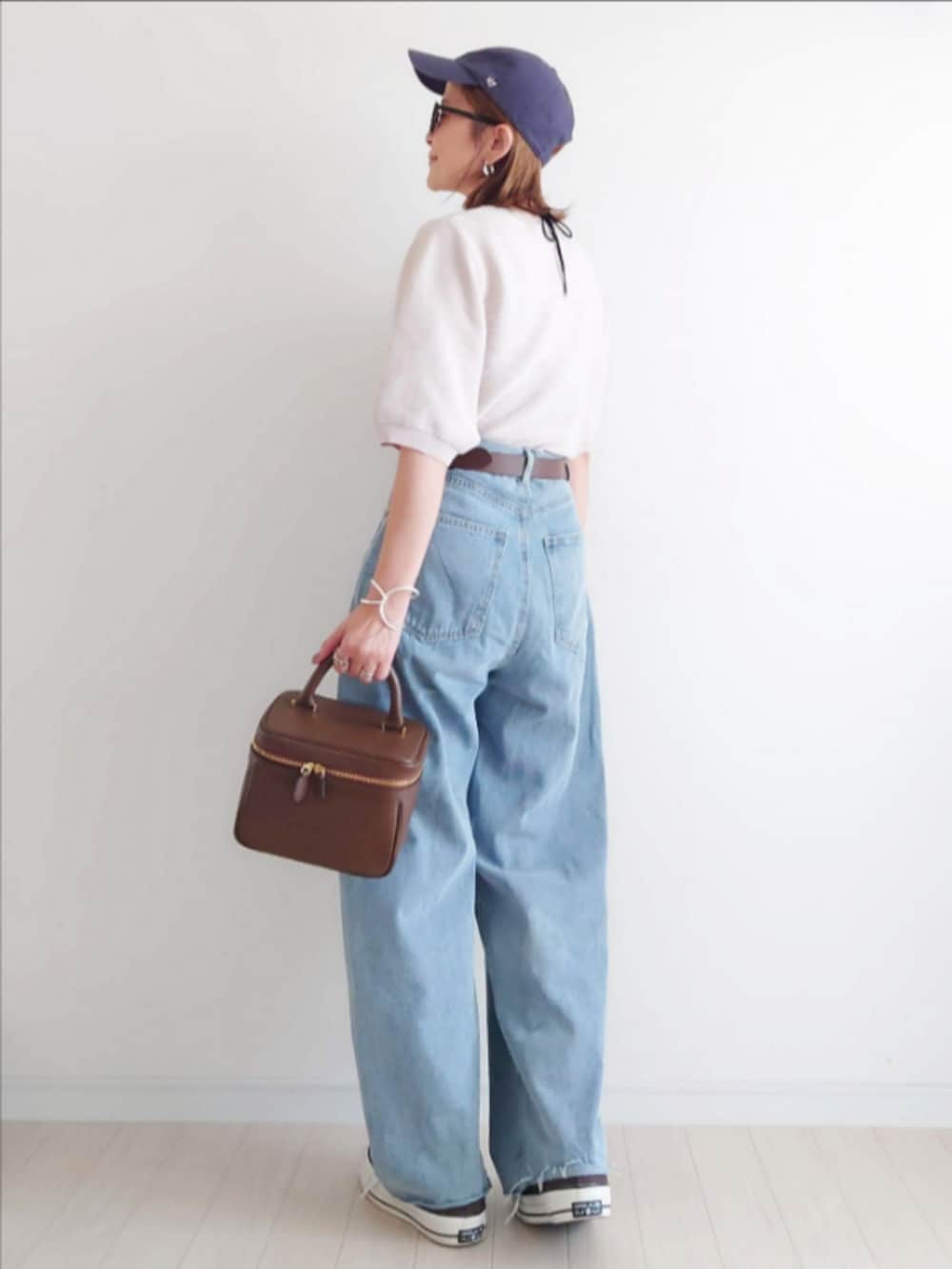 ホワイト系のニット/セーター、ブルー系のデニムパンツ、ブラウン系のハンドバッグを着用したレディースの秋コーディネートの3枚目の写真