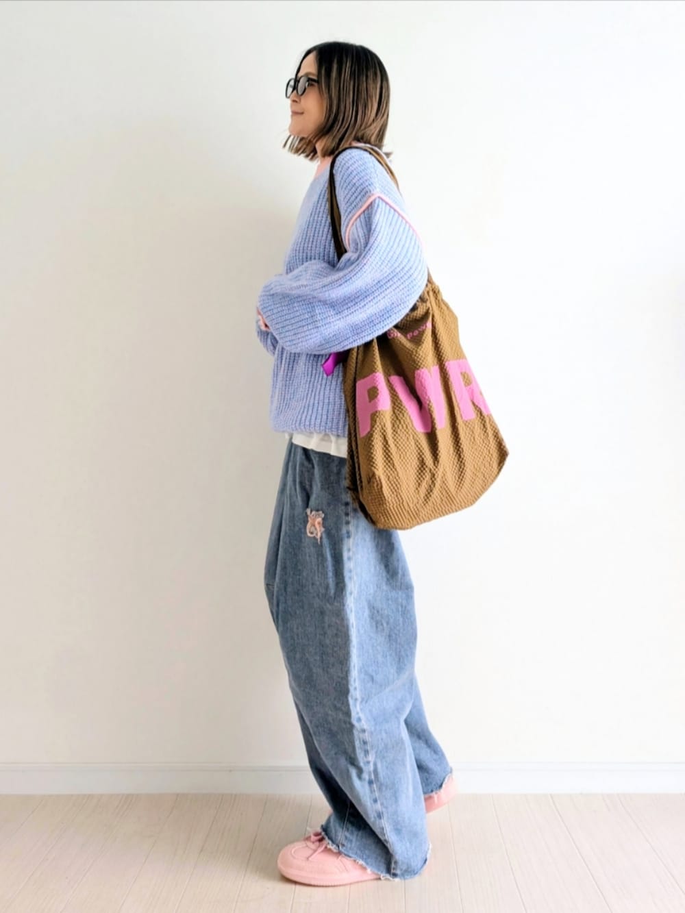 ピンク系のニット/セーター、ブルー系のデニムパンツ、ピンク系のスニーカーを着用したレディースの秋コーディネートの3枚目の写真