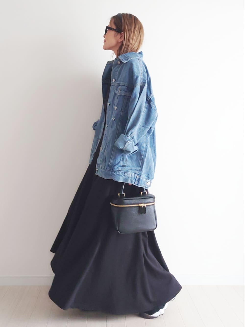 ブラック系のベスト、ブラック系のスカート、ブルー系のデニムジャケットを着用したレディースの春コーディネートの4枚目の写真