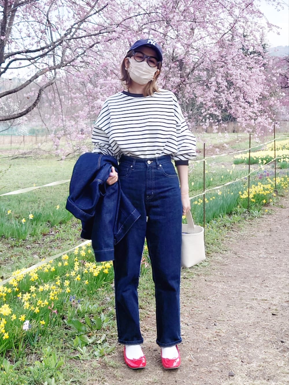 ブラック系のTシャツ/カットソー、ブルー系のデニムパンツ、ホワイト系のハンドバッグを着用したレディースの春コーディネートの5枚目の写真