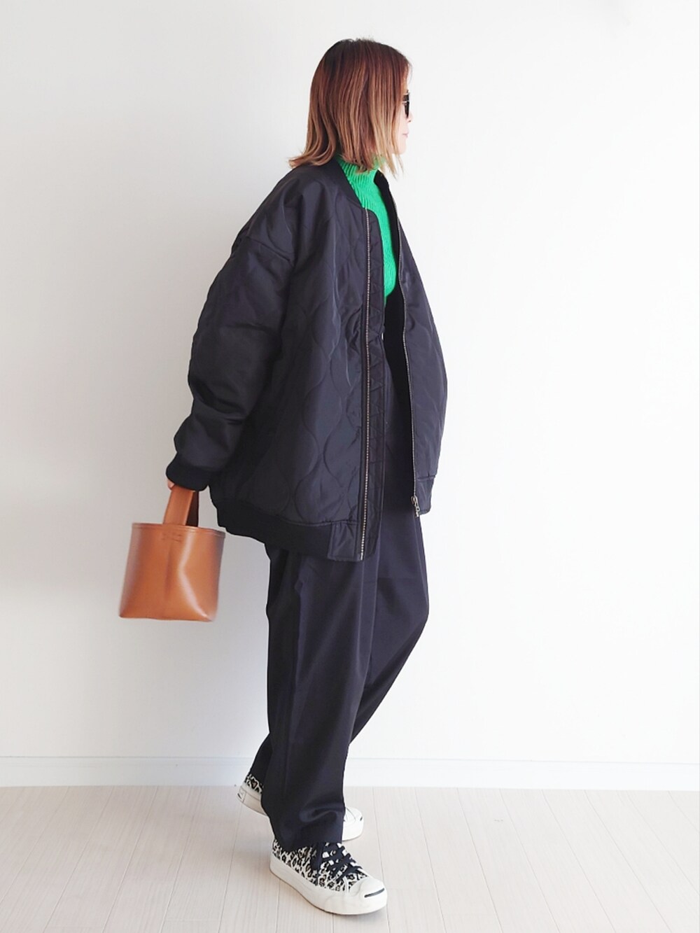 ブラック系のブルゾン、ブラック系のスラックス、グリーン系のニット/セーターを着用したレディースの冬コーディネートの3枚目の写真