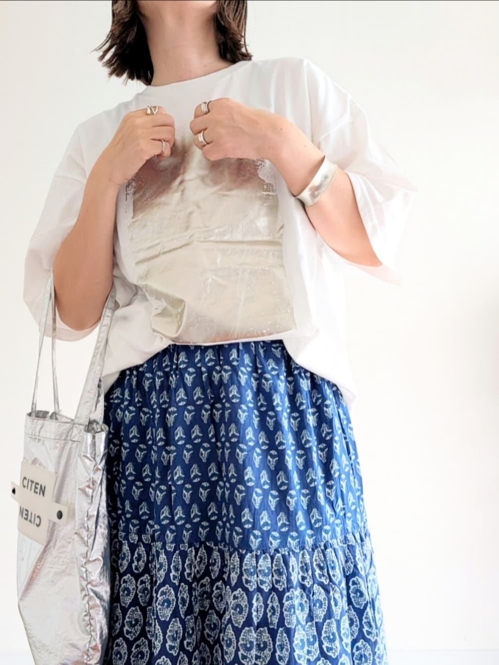 ブルー系のスカート、ホワイト系のTシャツ/カットソー、シルバー系のトートバッグを着用したレディースの夏コーディネートの5枚目の写真