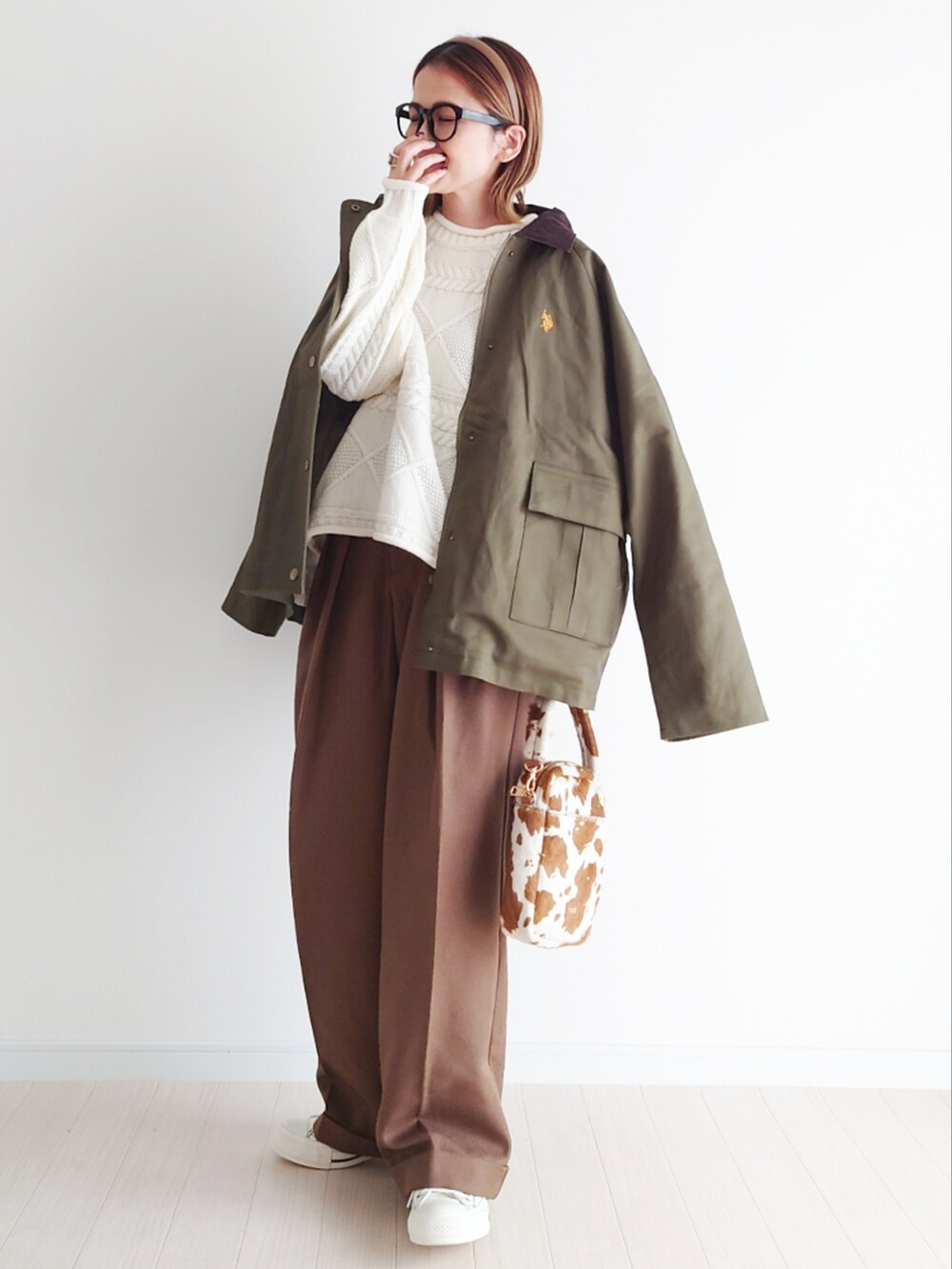 グリーン系のカバーオール、ホワイト系のニット/セーター、ブラウン系のパンツを着用したレディースの冬コーディネートの2枚目の写真