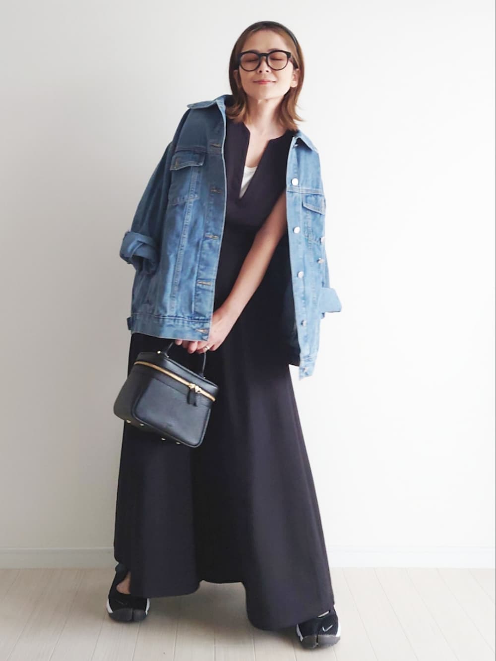 ブラック系のベスト、ブラック系のスカート、ブルー系のデニムジャケットを着用したレディースの春コーディネートの3枚目の写真