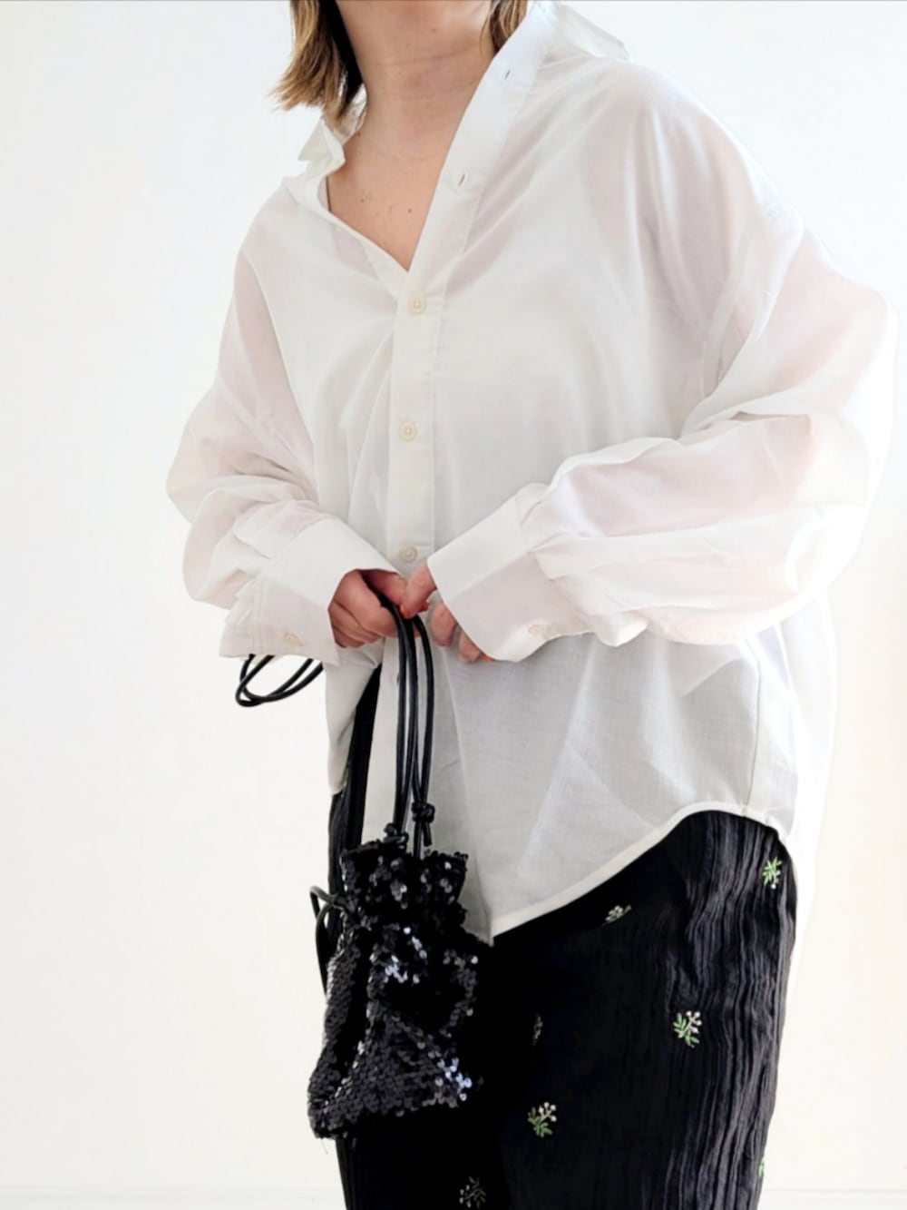 ブラック系のスラックス、ブラック系のショルダーバッグ、グリーン系のスニーカーを着用したレディースの春コーディネートの5枚目の写真