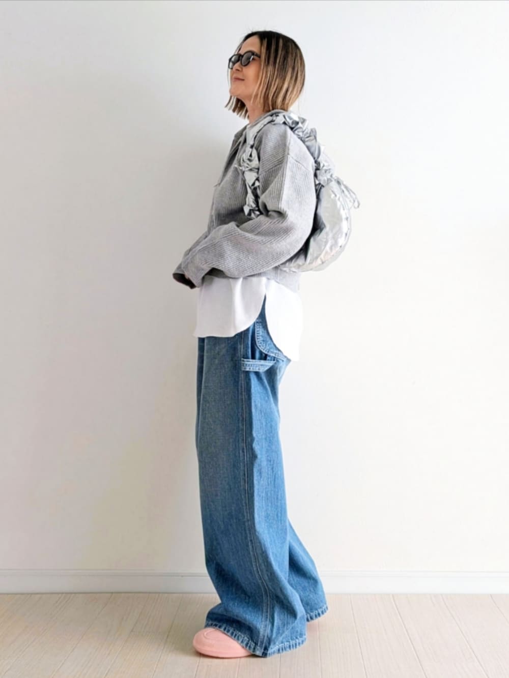 ブルー系のデニムパンツ、グレー系のパーカー、ピンク系のスニーカーを着用したレディースの冬コーディネートの2枚目の写真