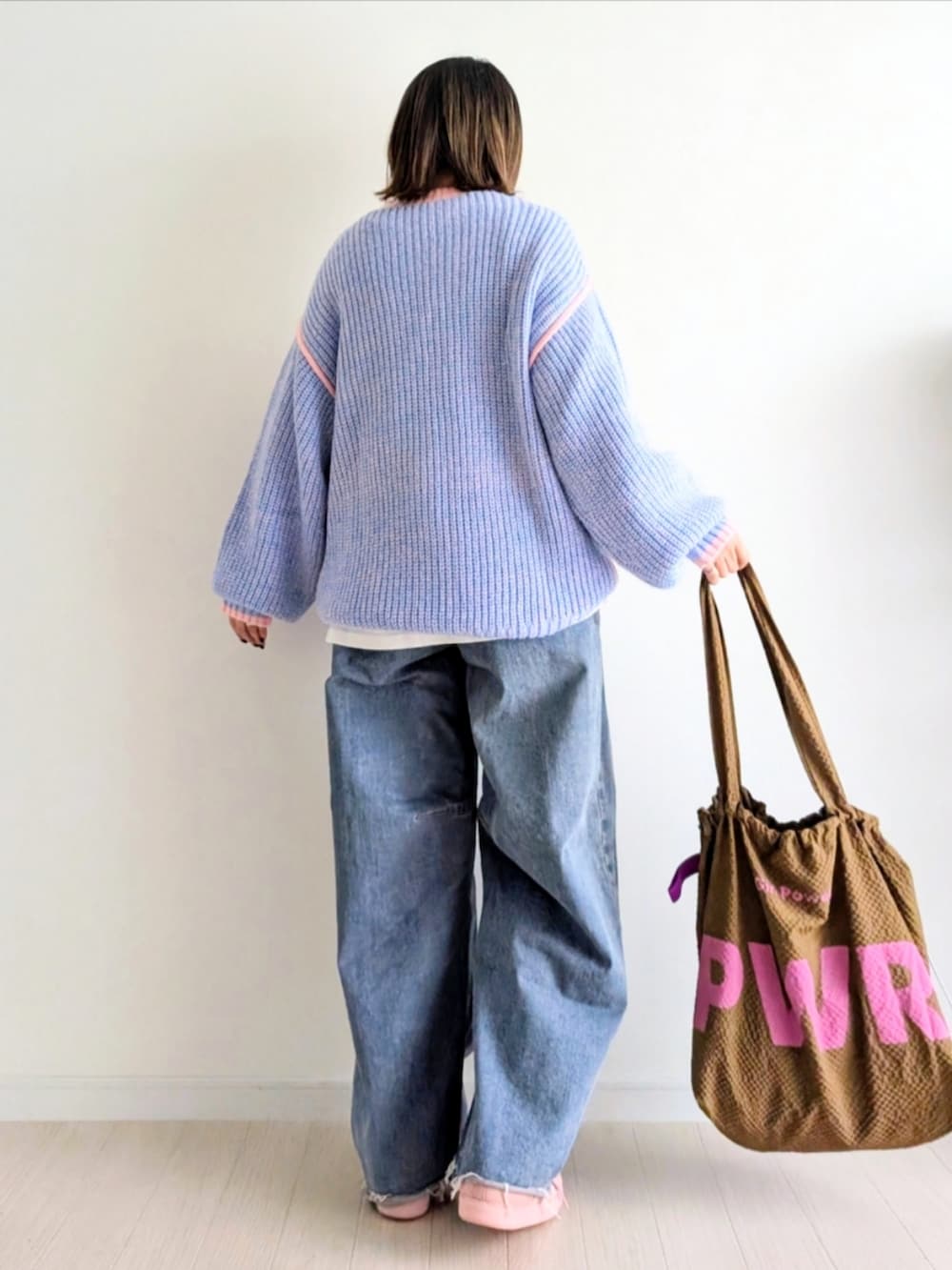 ピンク系のニット/セーター、ブルー系のデニムパンツ、ピンク系のスニーカーを着用したレディースの秋コーディネートの4枚目の写真