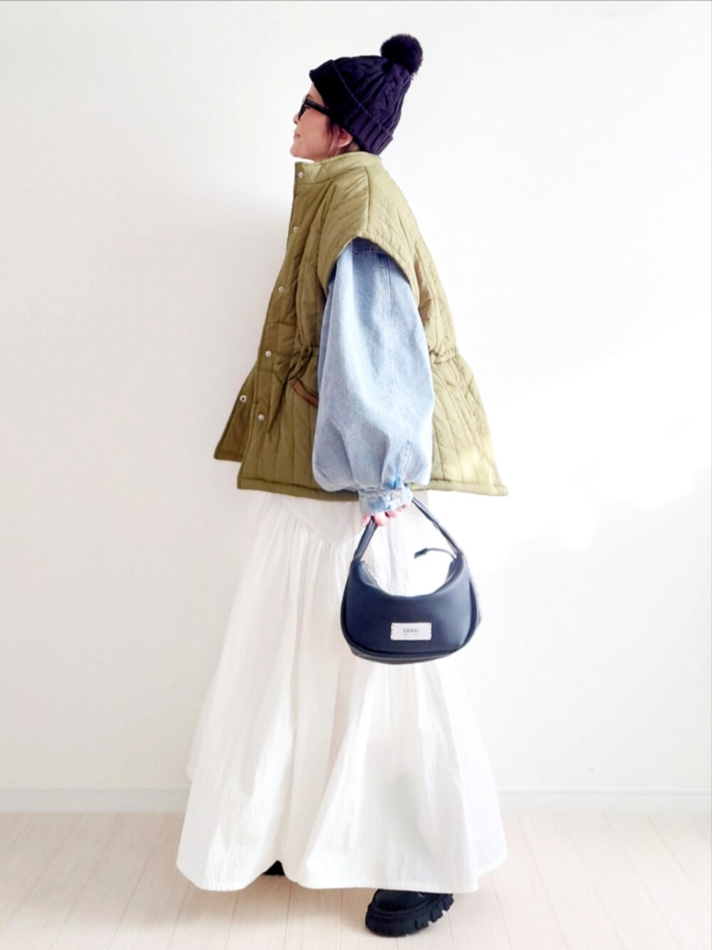 ブルー系のデニムジャケット、ホワイト系のスカート、ブラック系のブーツを着用したレディースの冬コーディネートの2枚目の写真