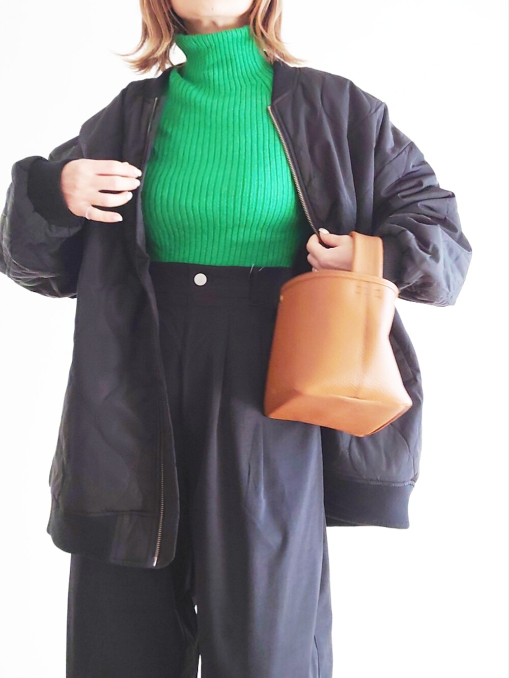 ブラック系のブルゾン、ブラック系のスラックス、グリーン系のニット/セーターを着用したレディースの冬コーディネートの5枚目の写真