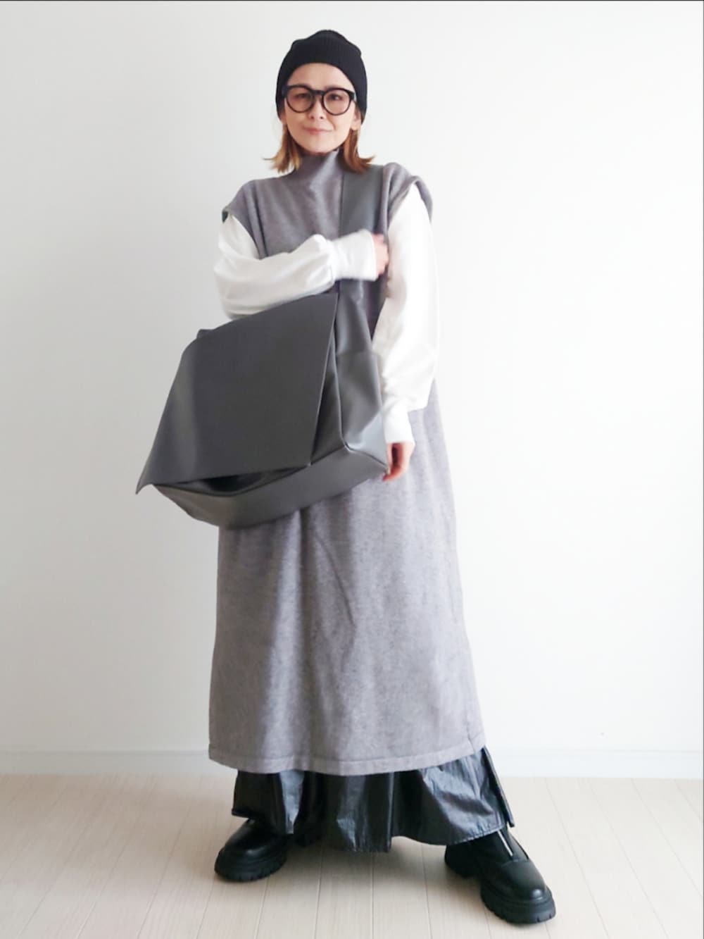 グレー系のワンピース、グレー系のショルダーバッグ、ブラック系のブーツを着用したレディースの秋コーディネートの2枚目の写真