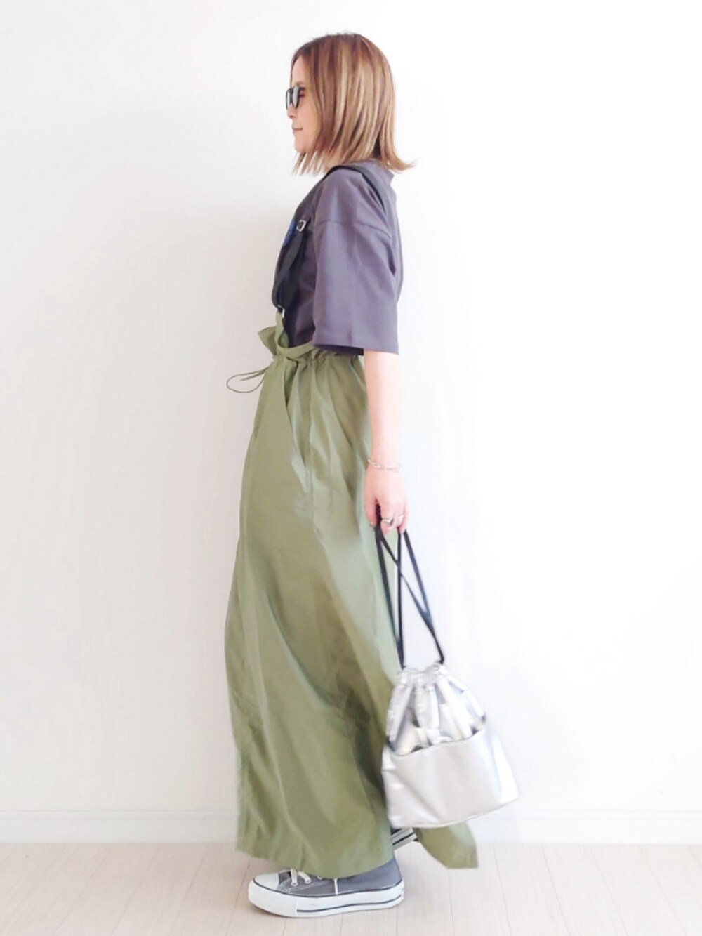 グレー系のTシャツ/カットソー、グリーン系のジャンパースカート、シルバー系のハンドバッグを着用したレディースの夏コーディネートの2枚目の写真