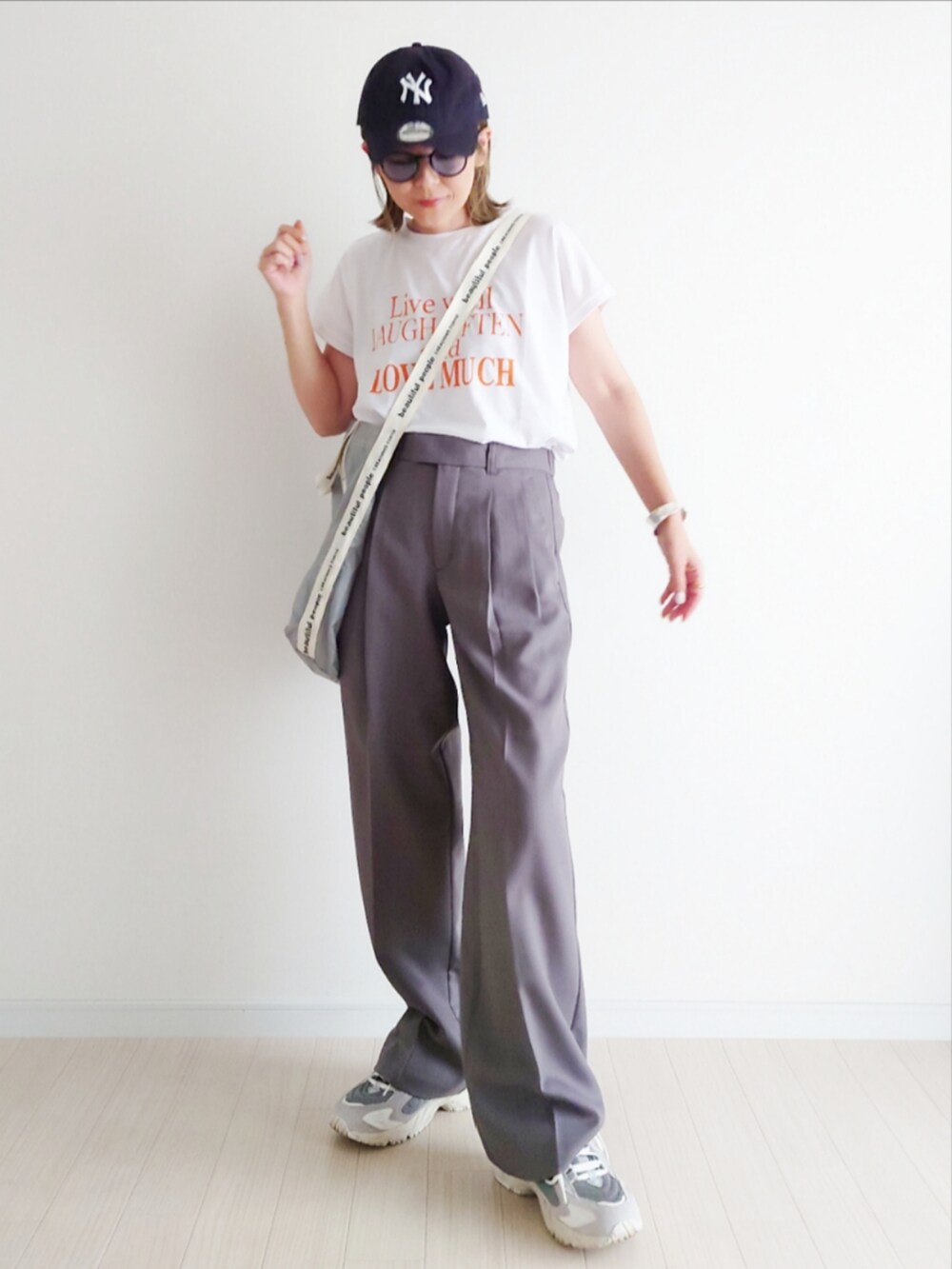 ホワイト系のTシャツ/カットソー、グレー系のスラックス、グレー系のスニーカーを着用したレディースの夏コーディネートの3枚目の写真