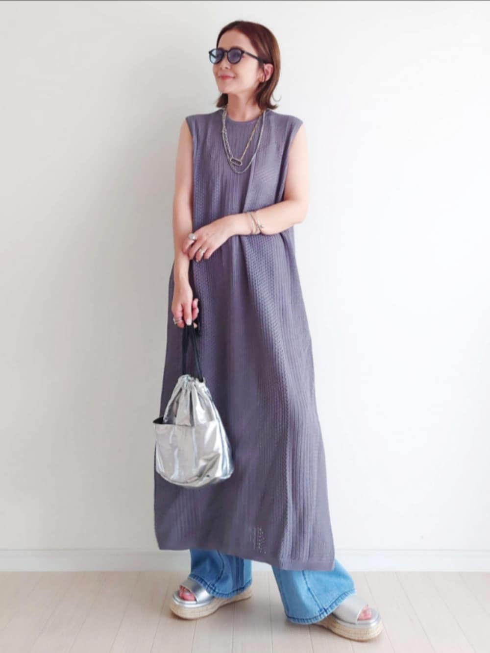 シルバー系のサンダル、ブルー系のデニムパンツ、グレー系のワンピースを着用したレディースの夏コーディネートの2枚目の写真