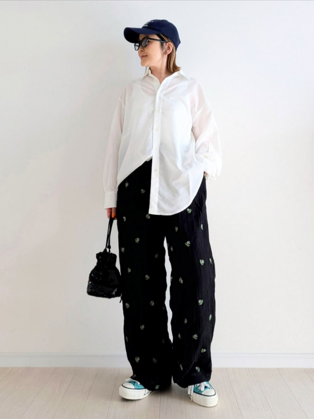 ブラック系のスラックス、ブラック系のショルダーバッグ、グリーン系のスニーカーを着用したレディースの春コーディネートの4枚目の写真