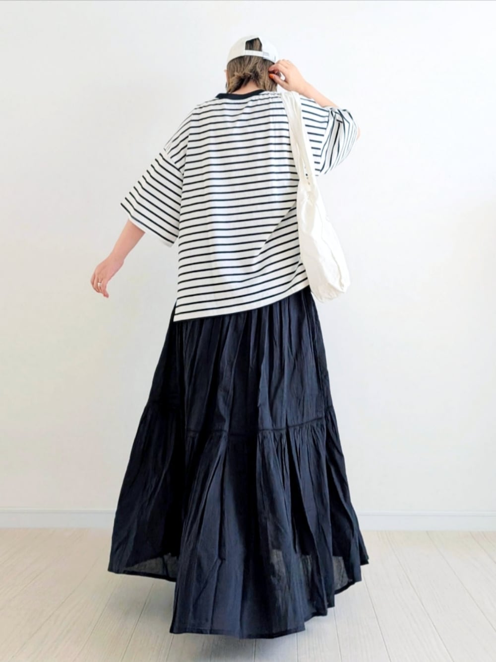 ブラック系のTシャツ/カットソー、ブラック系のスカート、ブラック系のスニーカーを着用したレディースの春コーディネートの3枚目の写真