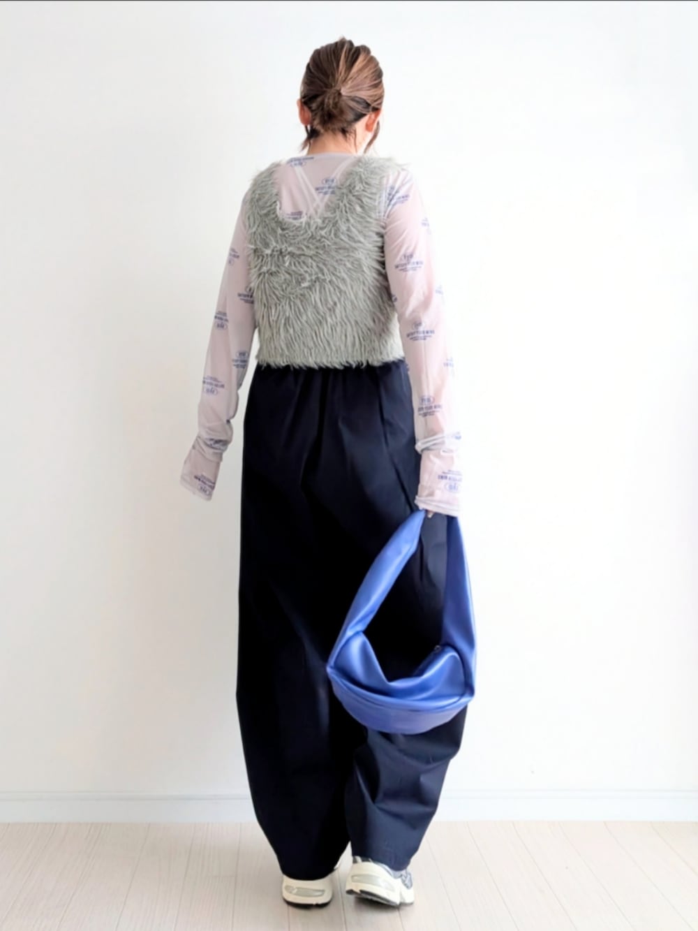 ベージュ系のベスト、ブルー系のチノパンツ、ブルー系のハンドバッグを着用したレディースの春コーディネートの3枚目の写真