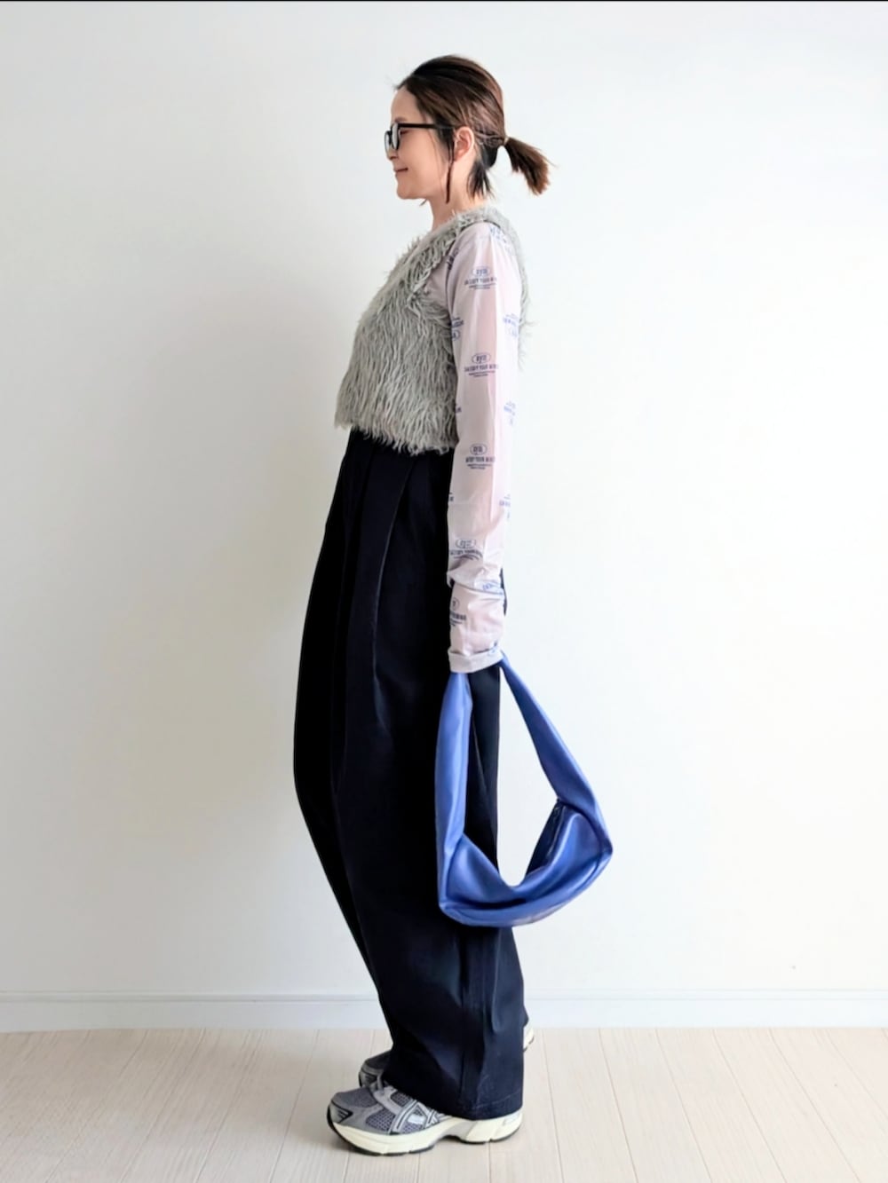 ベージュ系のベスト、ブルー系のチノパンツ、ブルー系のハンドバッグを着用したレディースの春コーディネートの2枚目の写真