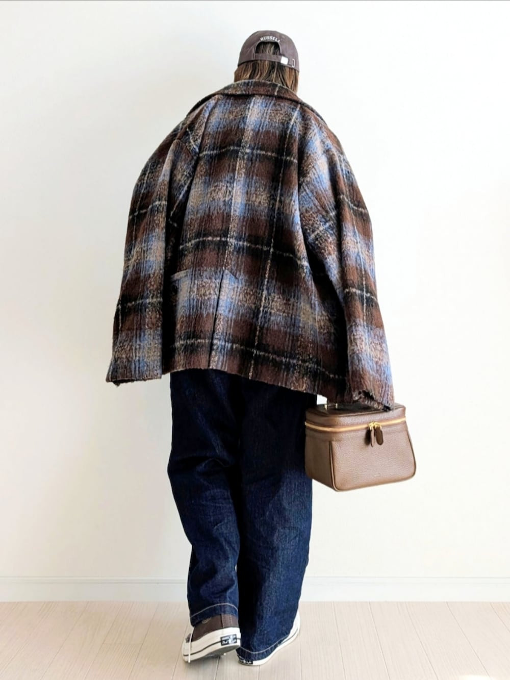 ブラウン系のテーラードジャケット、ベージュ系のニット/セーター、ブルー系のデニムパンツを着用したレディースの秋コーディネートの3枚目の写真