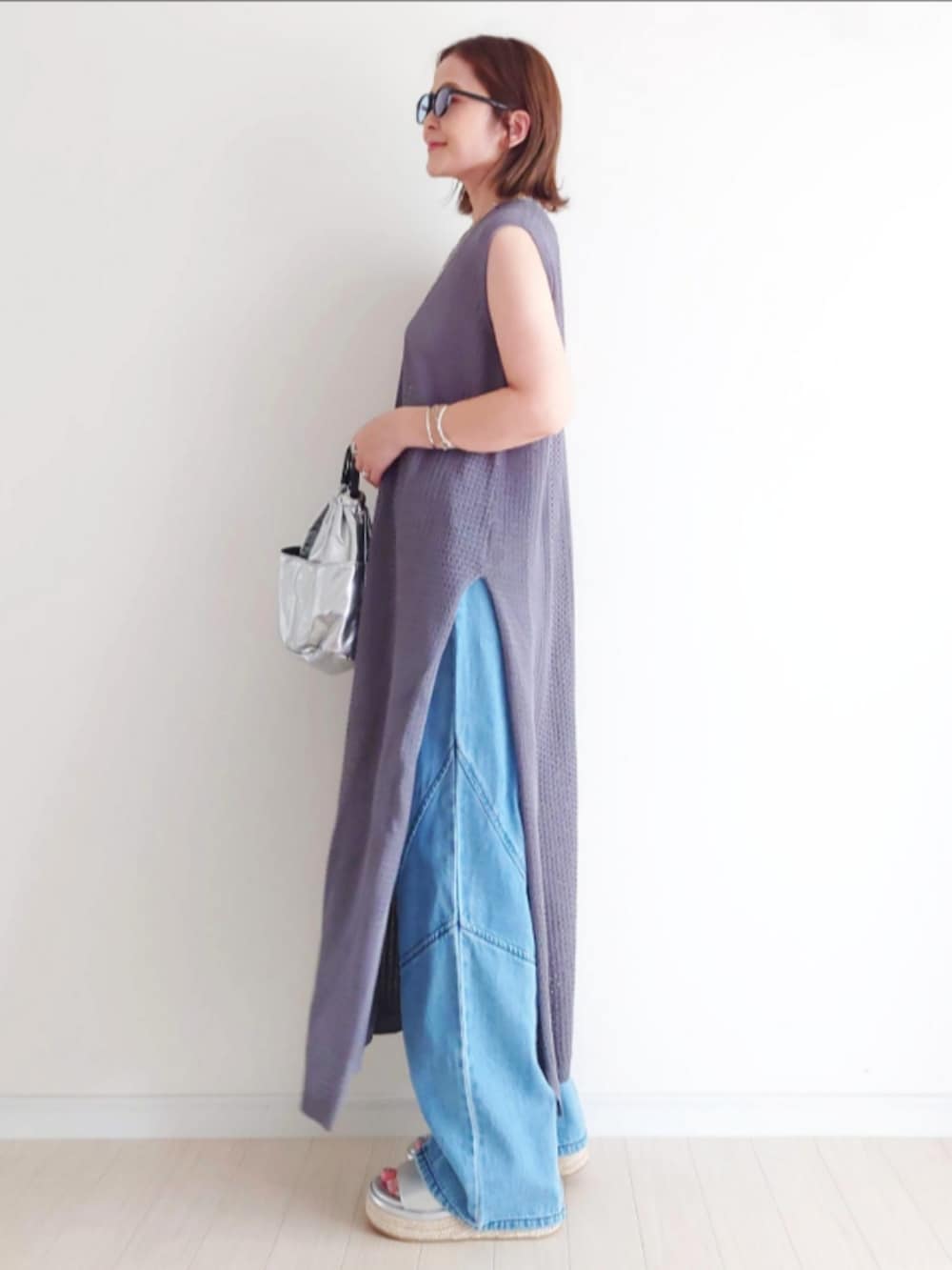 シルバー系のサンダル、ブルー系のデニムパンツ、グレー系のワンピースを着用したレディースの夏コーディネートの3枚目の写真