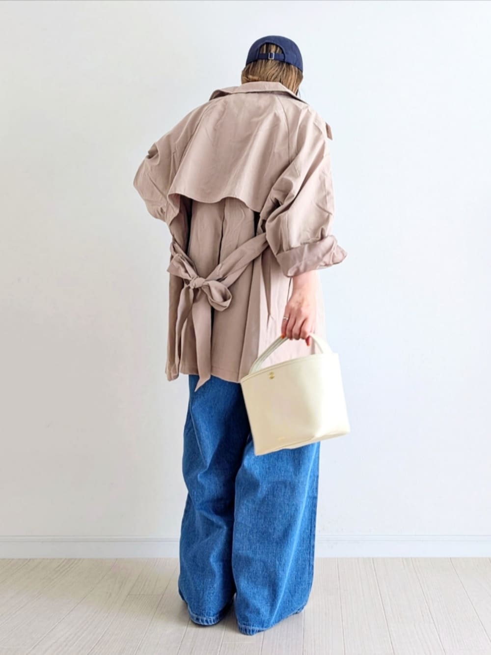 ブルー系のデニムパンツ、ベージュ系のトレンチコート、ホワイト系のスニーカーを着用したレディースの春コーディネートの3枚目の写真