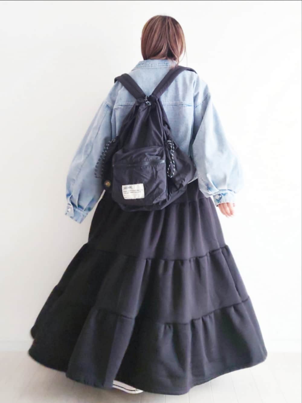 ブルー系のデニムジャケット、ブラック系のバックパック/リュック、ブラック系のワンピースを着用したレディースの冬コーディネートの3枚目の写真