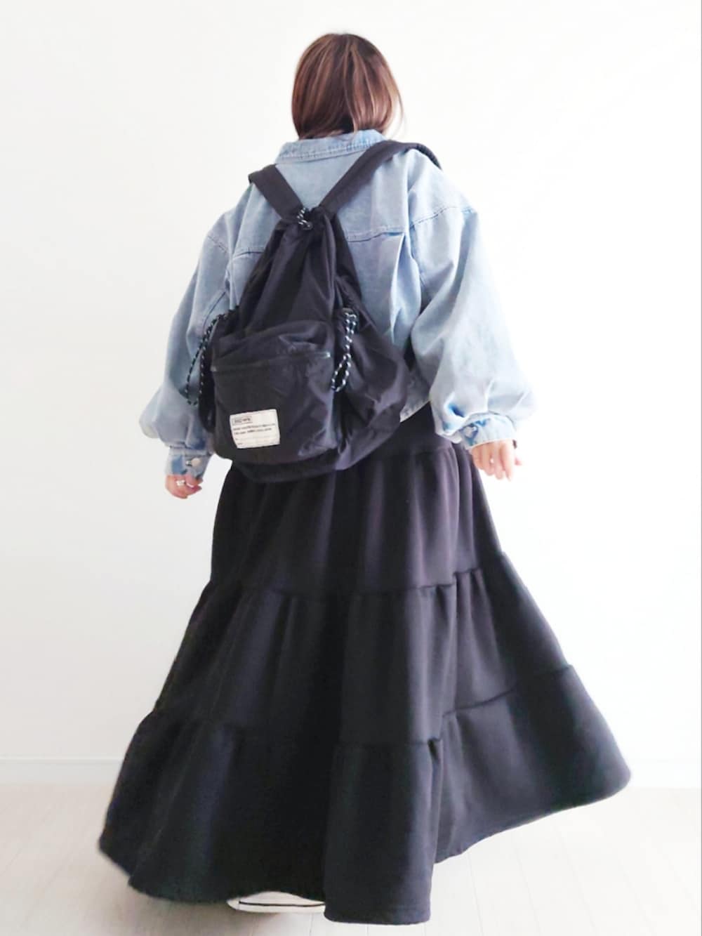 ブルー系のデニムジャケット、ブラック系のバックパック/リュック、ブラック系のワンピースを着用したレディースの冬コーディネートの4枚目の写真