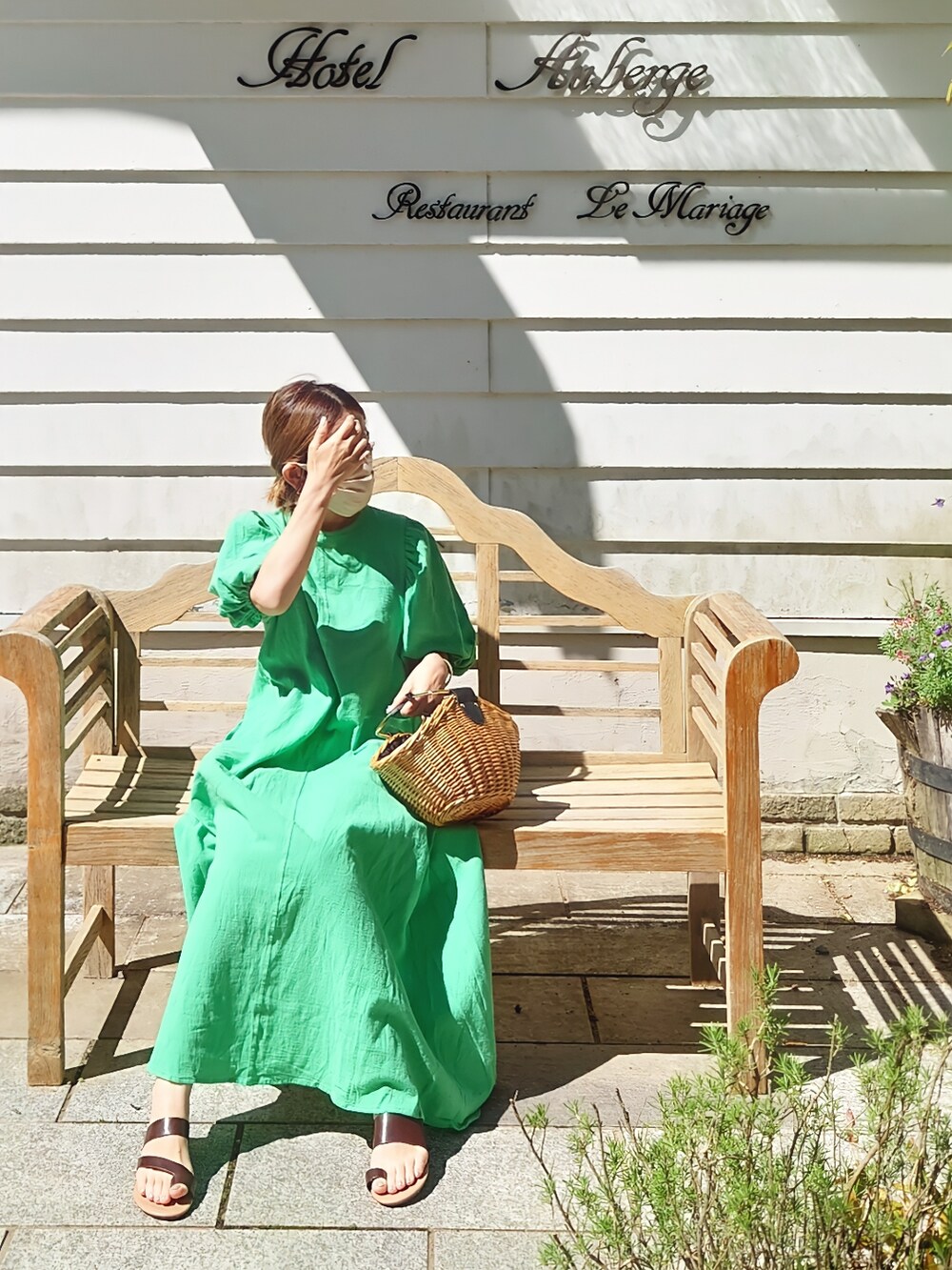 グリーン系のワンピース、ブラウン系のかごバッグ、ブラウン系のサンダルを着用したレディースの夏コーディネートの2枚目の写真