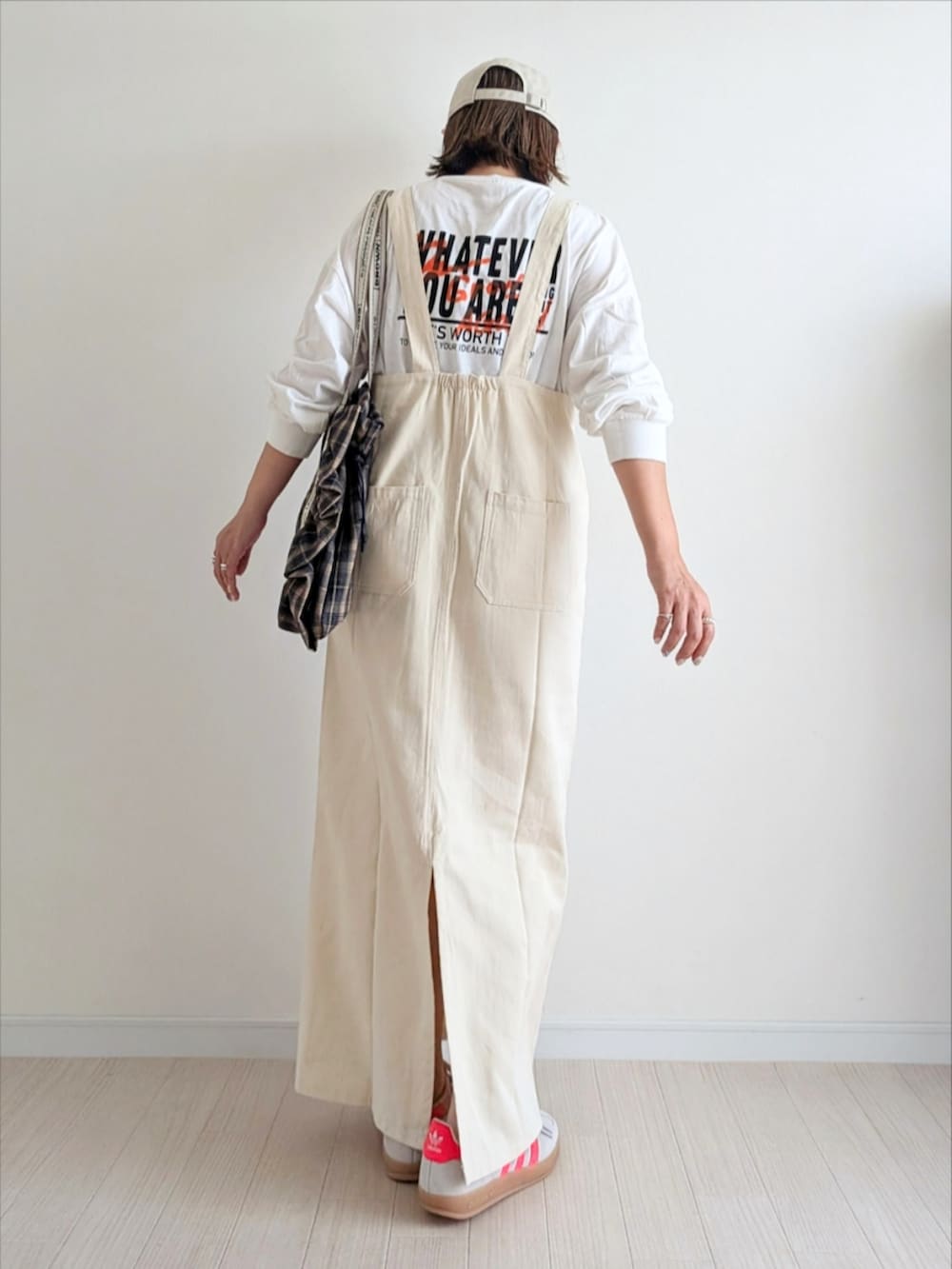 ホワイト系のジャンパースカート、ホワイト系のTシャツ/カットソー、ベージュ系のスニーカーを着用したレディースの秋コーディネートの3枚目の写真