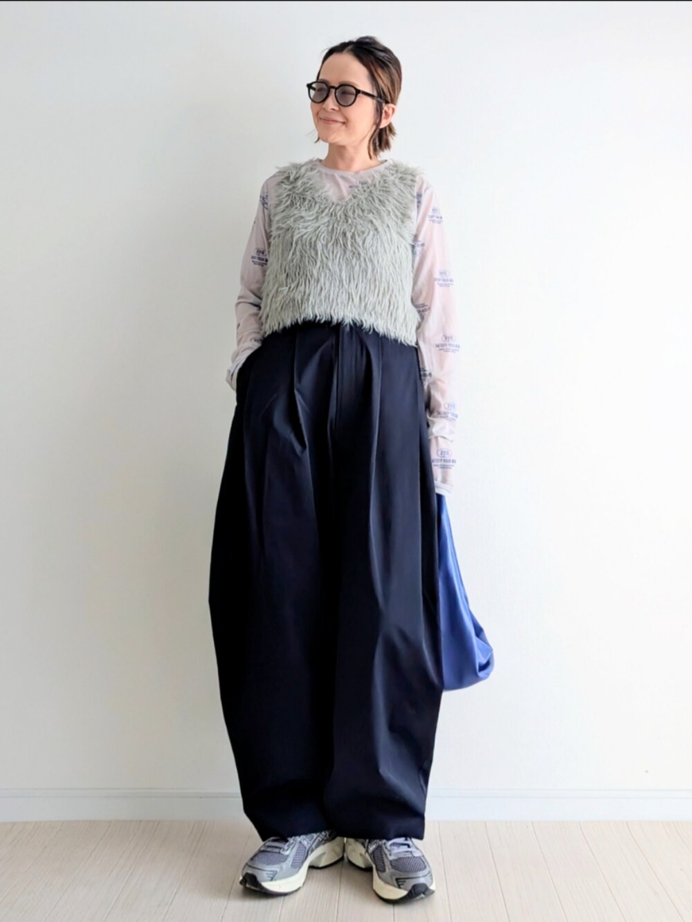 ベージュ系のベスト、ブルー系のチノパンツ、ブルー系のハンドバッグを着用したレディースの春コーディネートの4枚目の写真