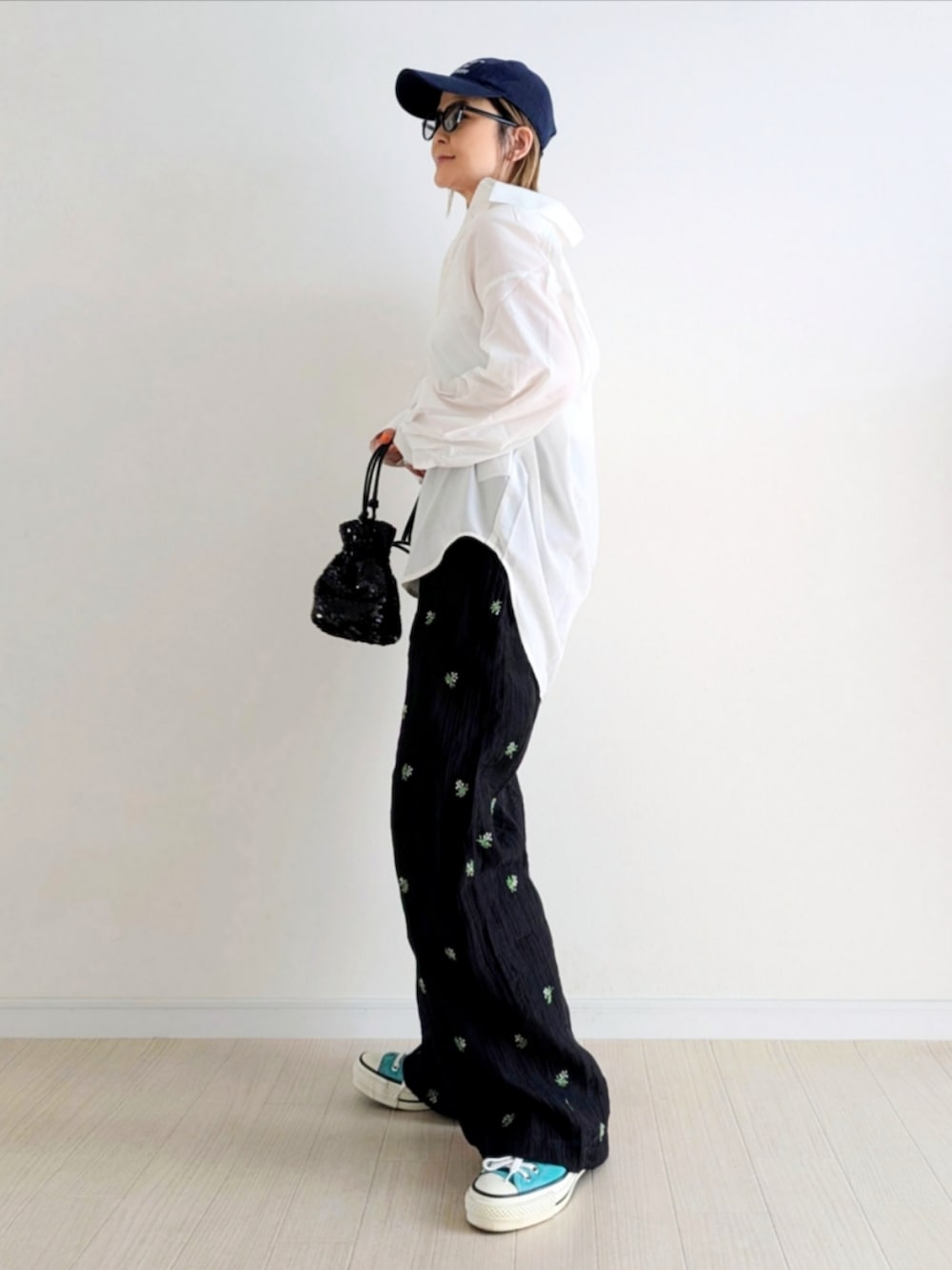 ブラック系のスラックス、ブラック系のショルダーバッグ、グリーン系のスニーカーを着用したレディースの春コーディネートの2枚目の写真