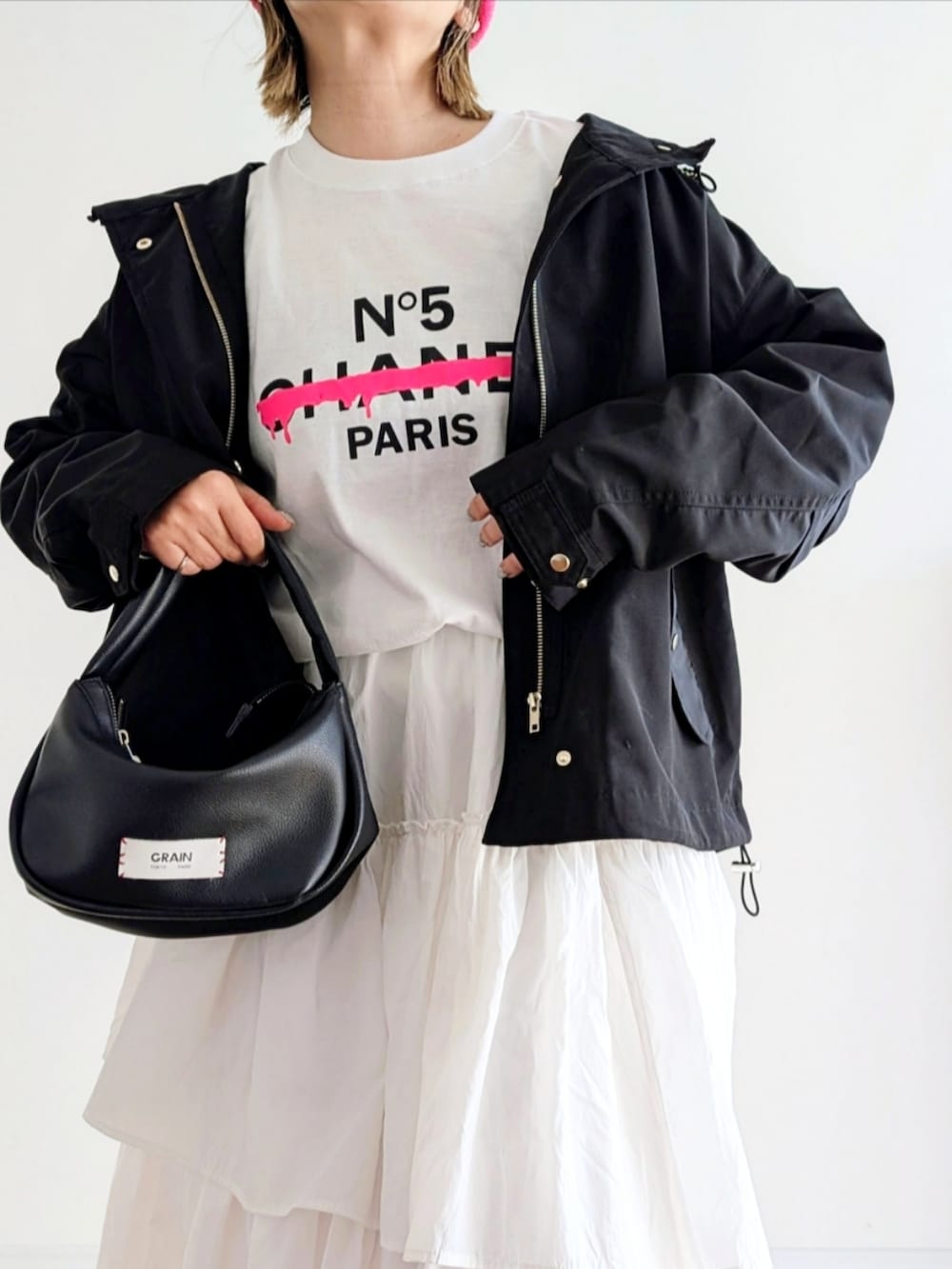 ホワイト系のスカート、ブラック系のハンドバッグ、ブラック系のマウンテンパーカーを着用したレディースの冬コーディネートの5枚目の写真